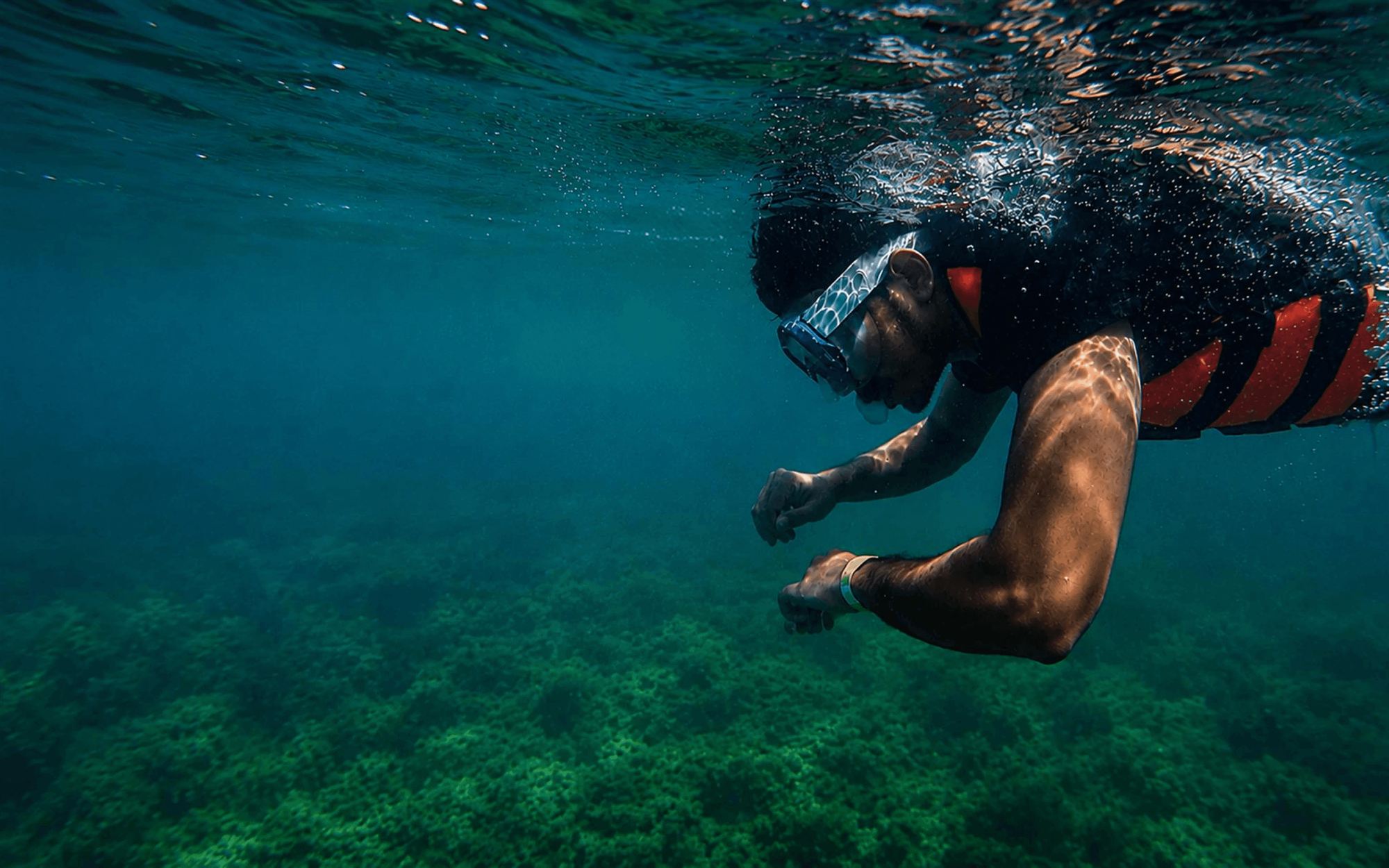 Pradyumn snorkelling just below the surface above a green reef